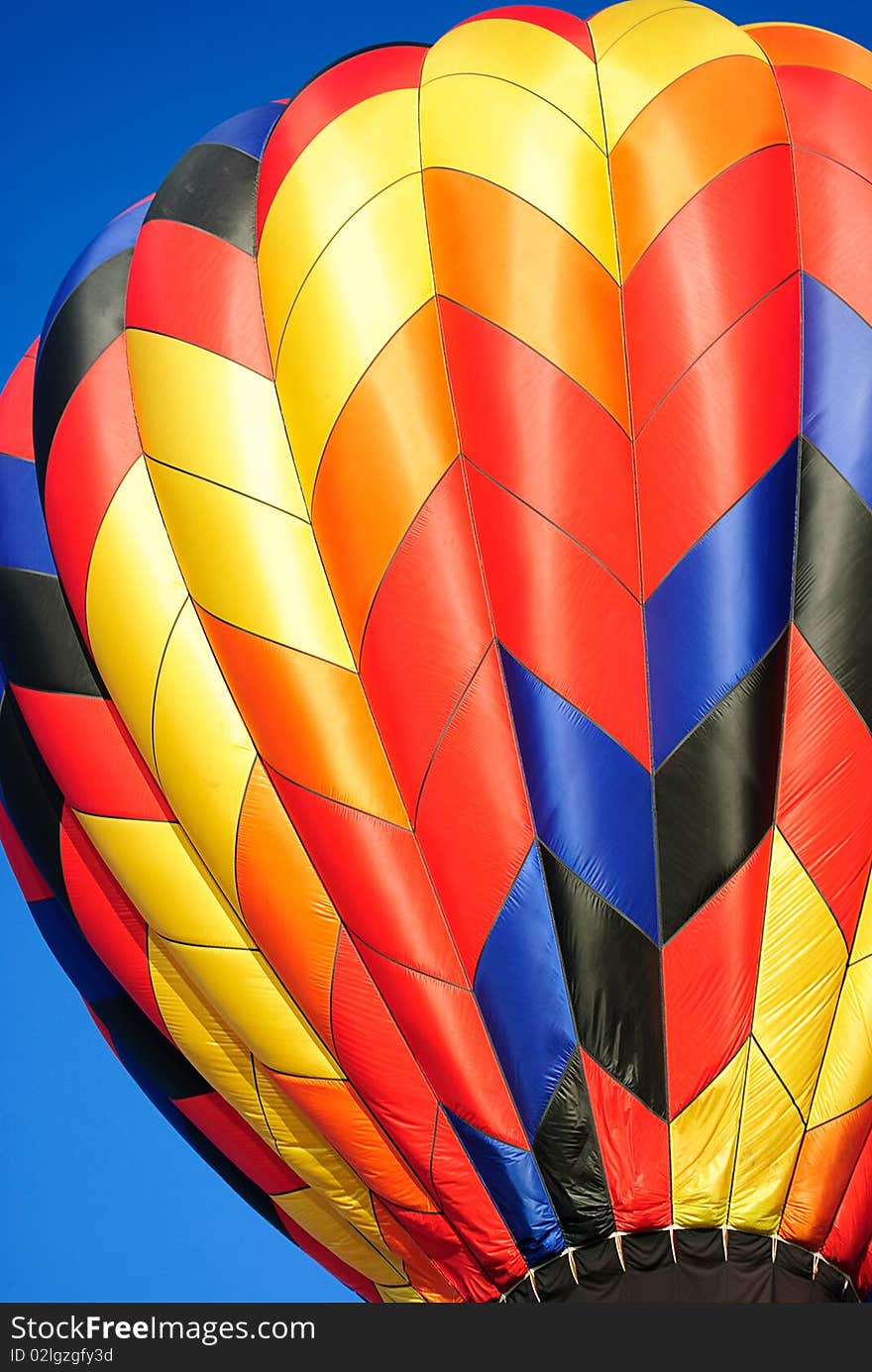 A Close up view of an hot air balloon with rainbow colors with blue sky