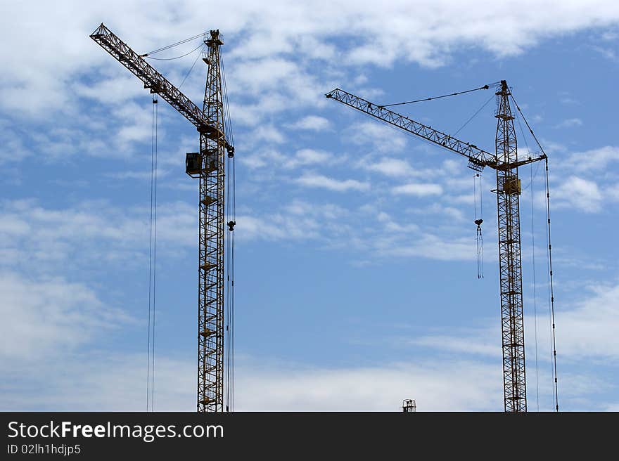 Elevating construction crane against the blue sky in a fair weather