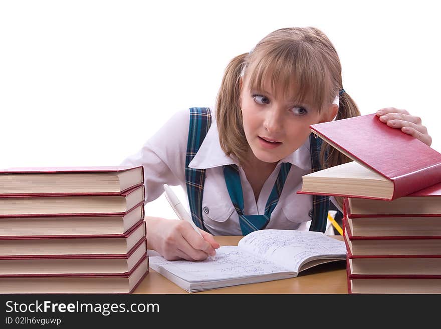 Girl studying hard for exams. Young and beautiful schoolgirl is wearing a traditional uniform watch furtively at the textbook. Girl studying hard for exams. Young and beautiful schoolgirl is wearing a traditional uniform watch furtively at the textbook.