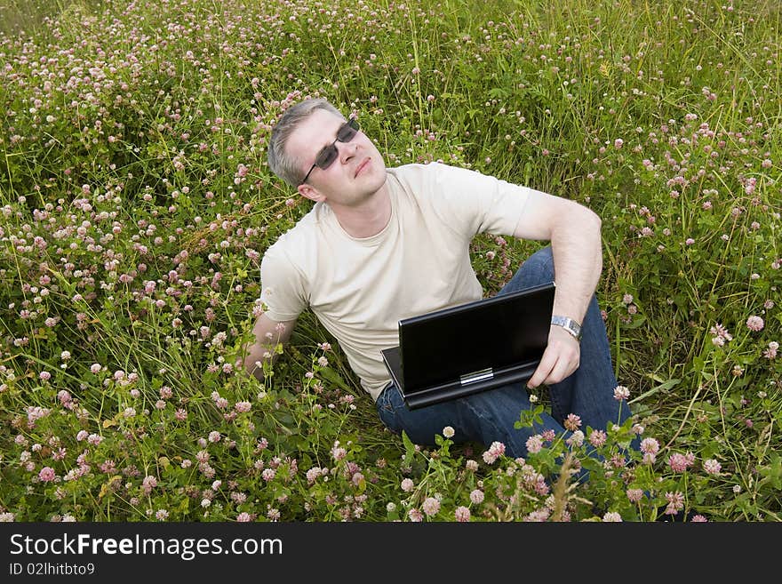 Man with laptop on meadow