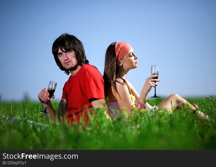 Long-haired girl in kerchief and boy with wineglasses on grass