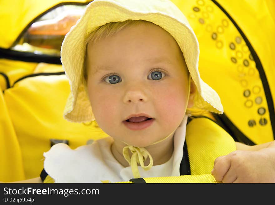 The surprised girl with blue eyes sits in a children's carriage. The surprised girl with blue eyes sits in a children's carriage