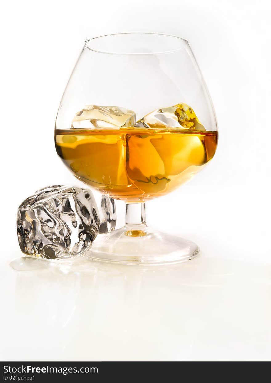 Glass of cognac with ice in a light environment. Glass of cognac with ice in a light environment