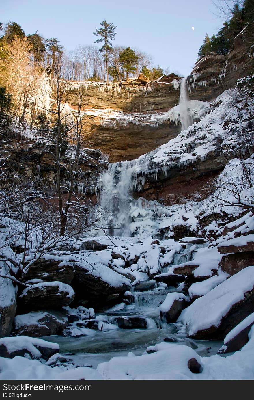 Waterfall landscape with mountains in the background in winter season with the moon in the sky. Waterfall landscape with mountains in the background in winter season with the moon in the sky.