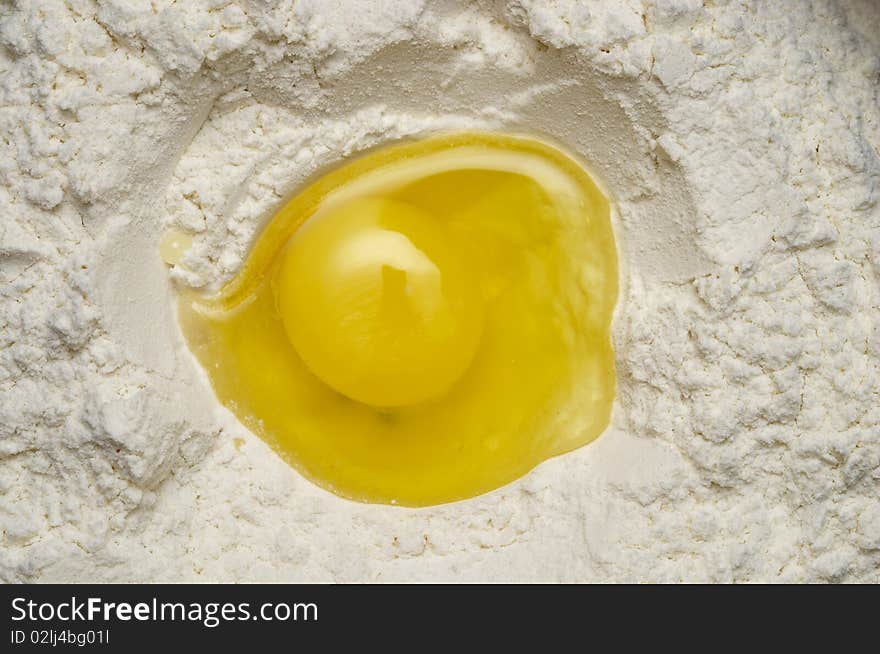 Smashed egg yolk inside the flour macro shot background. Smashed egg yolk inside the flour macro shot background