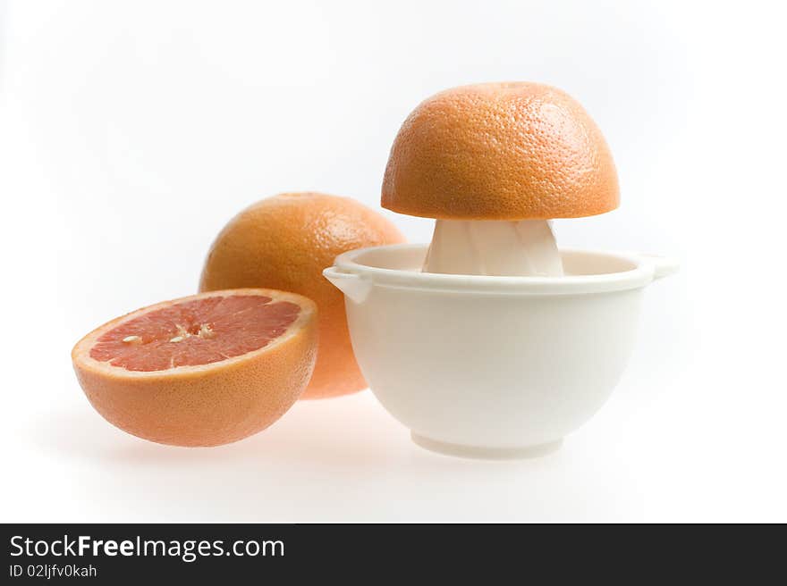 Red grapefruit being squeezed by hand isolated on white background