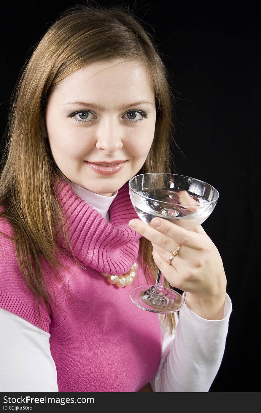 The young woman drinks water from a glass the black background. The young woman drinks water from a glass the black background