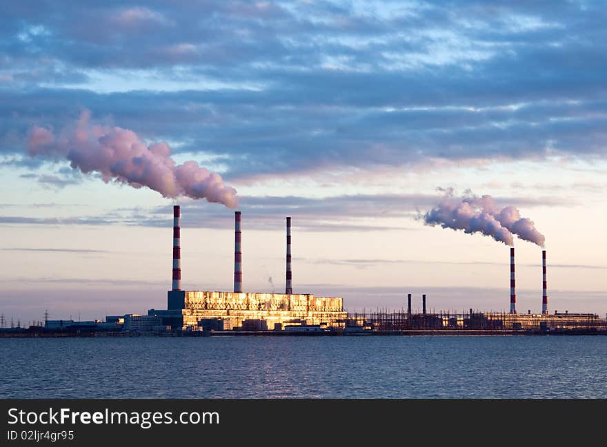 Thermal power station and smoke plume  lit golden sun rays.