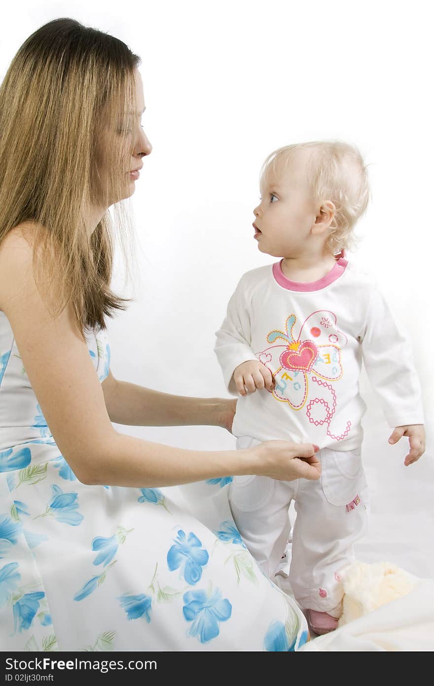 Careful mother dresses the daughter. Isolated on white.