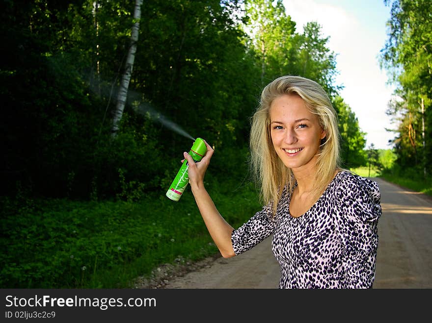 Young beautiful woman is polluting forest with hair spray. Young beautiful woman is polluting forest with hair spray