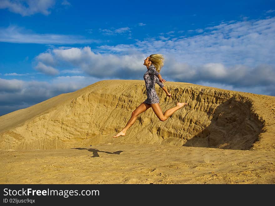 Young beautiful woman is having fun while sun is shinging and she jumping in the sand. Young beautiful woman is having fun while sun is shinging and she jumping in the sand.