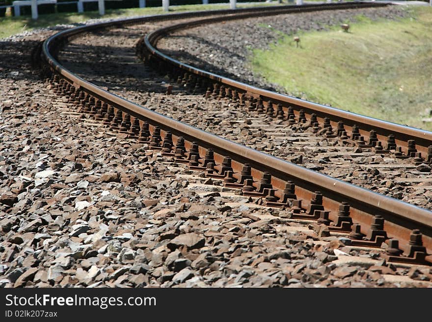 Railway line in an arc on summer. The sun is shining to the rails. Railway line in an arc on summer. The sun is shining to the rails.