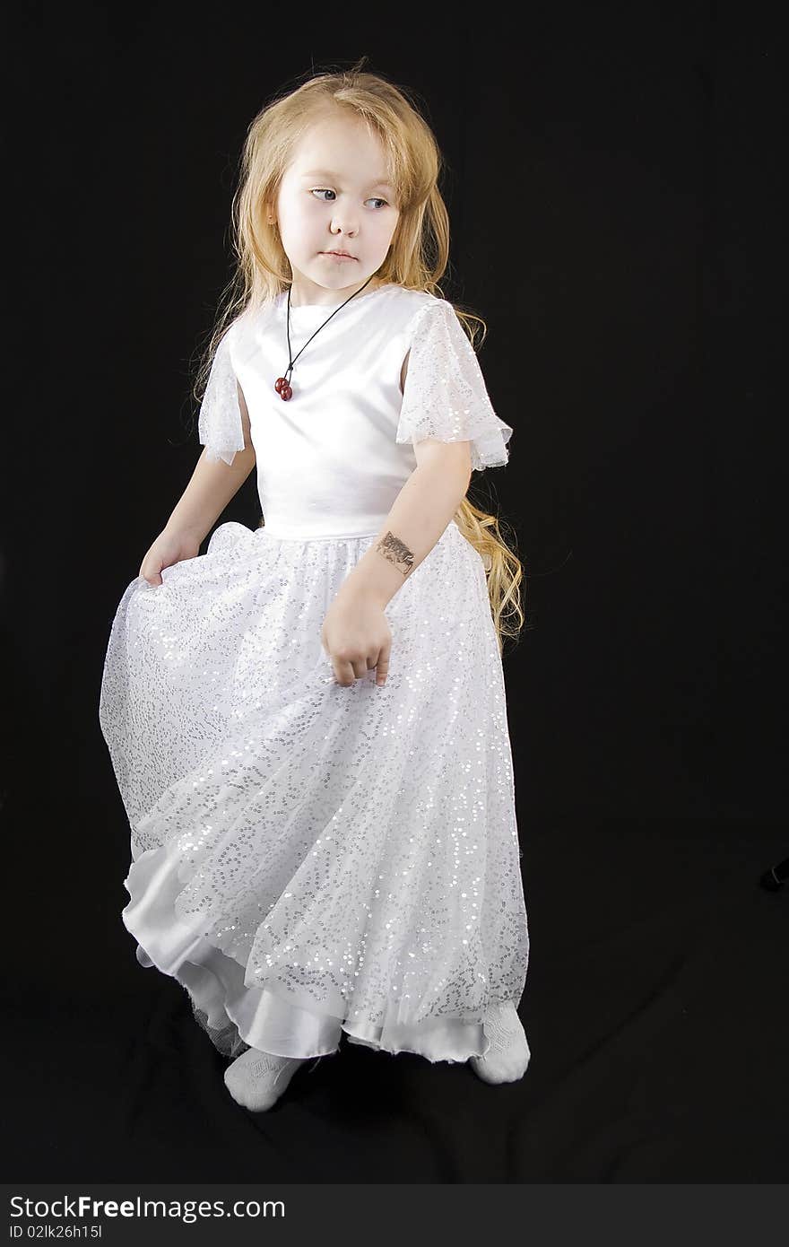 The girl the princess in a white dress standing opposite to a black background. The girl the princess in a white dress standing opposite to a black background
