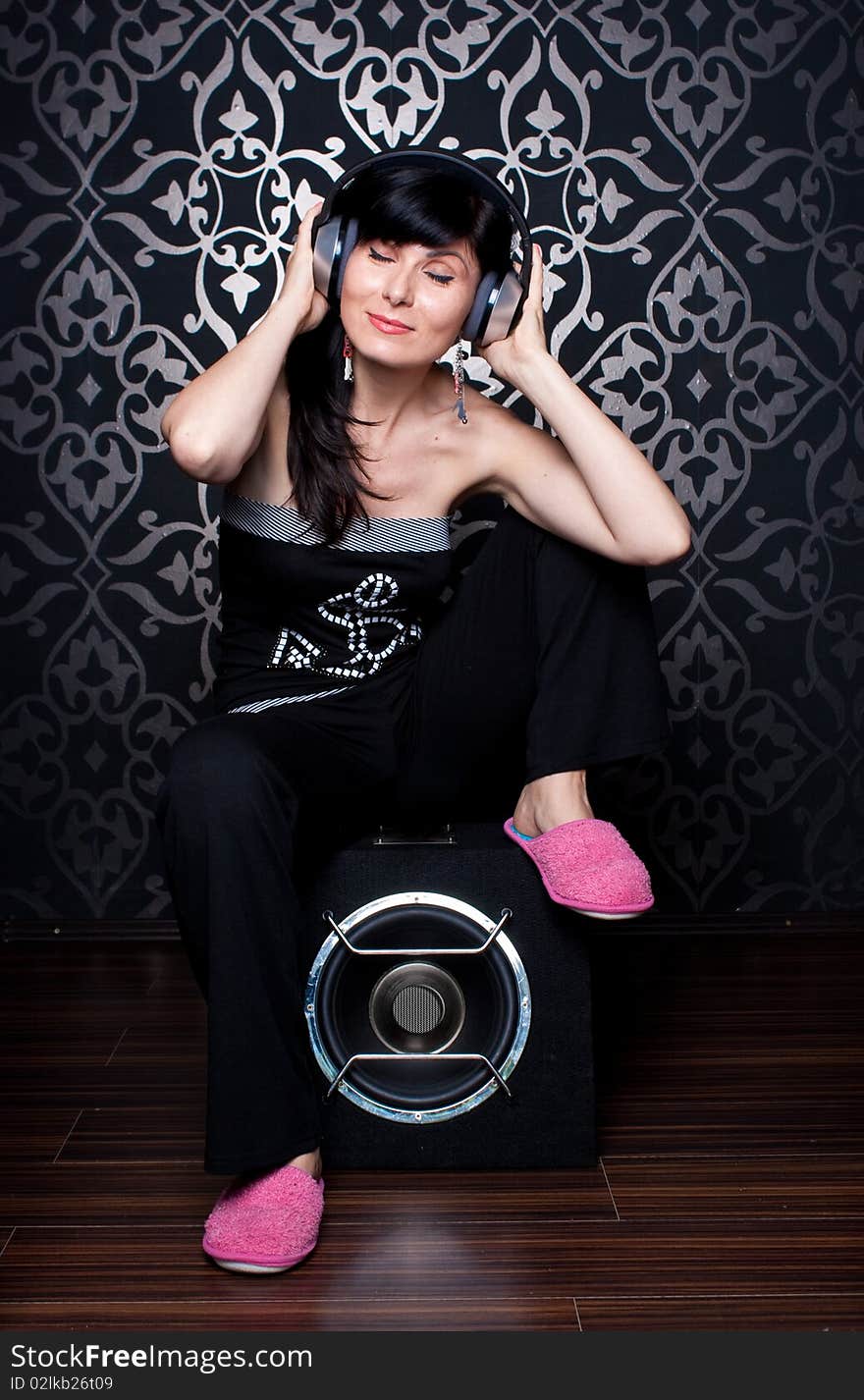 Cool girl sitting on a subwoofer with headphones on. Cool girl sitting on a subwoofer with headphones on