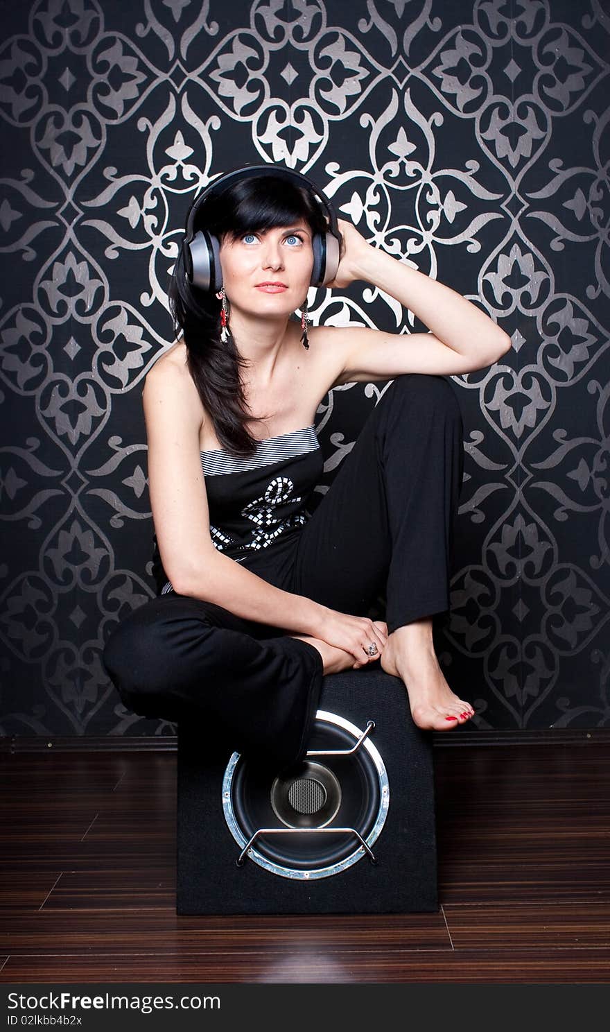 Cool girl sitting on a subwoofer with headphones on. Cool girl sitting on a subwoofer with headphones on