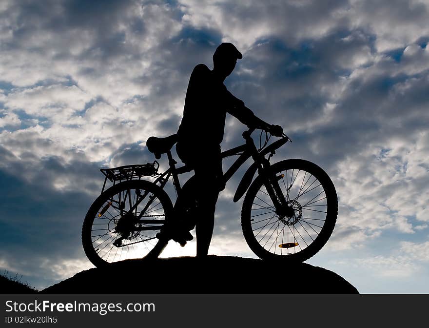 Biker silhouette opposite cloudy sky