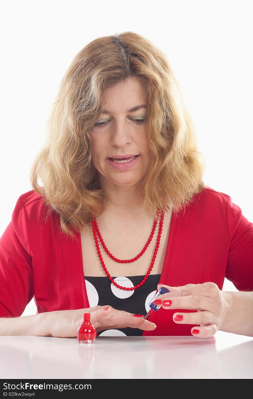 Middle-aged woman in red painting her nails - isolated on white. Middle-aged woman in red painting her nails - isolated on white