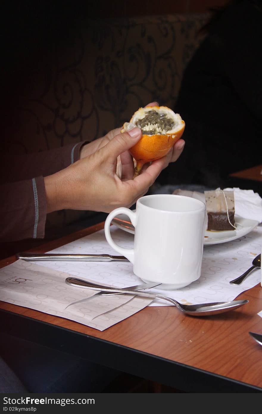 Woman holding a passion fruit for breakfast with cup of tea. Woman holding a passion fruit for breakfast with cup of tea