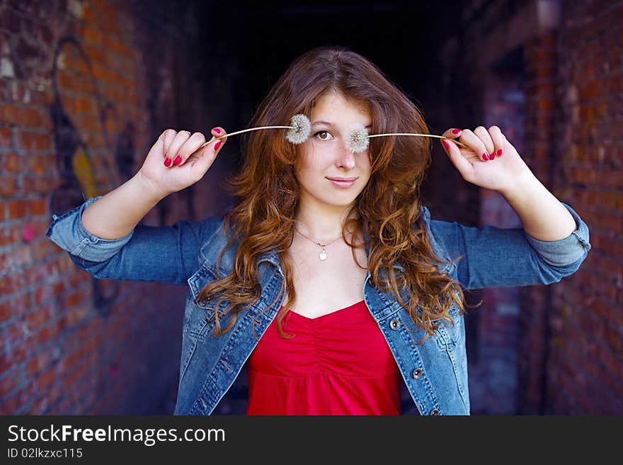 Girl closing one eye with dandelion. Girl closing one eye with dandelion