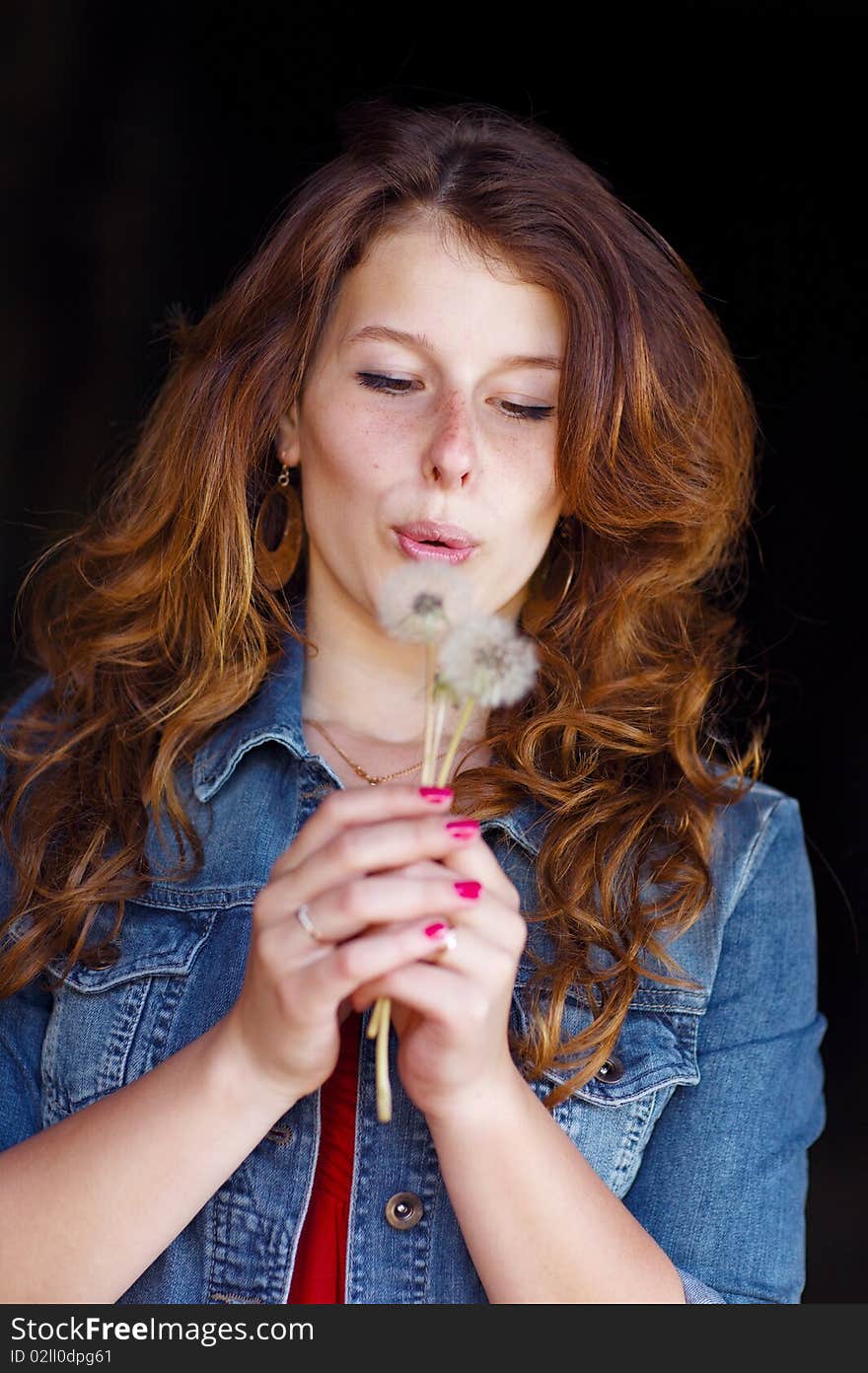 Young girl blowing on two dandelions