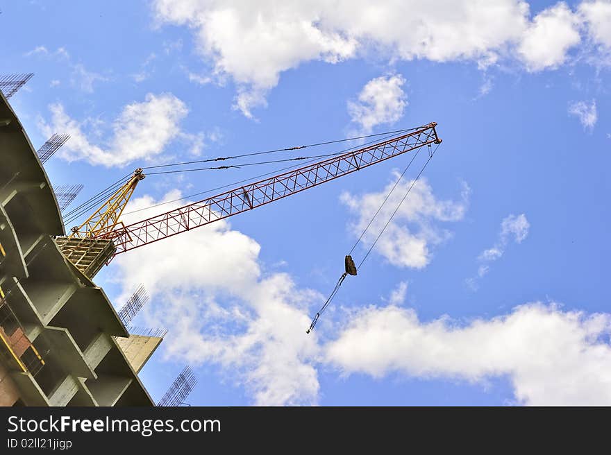 Building with elevating crane and clouds on background