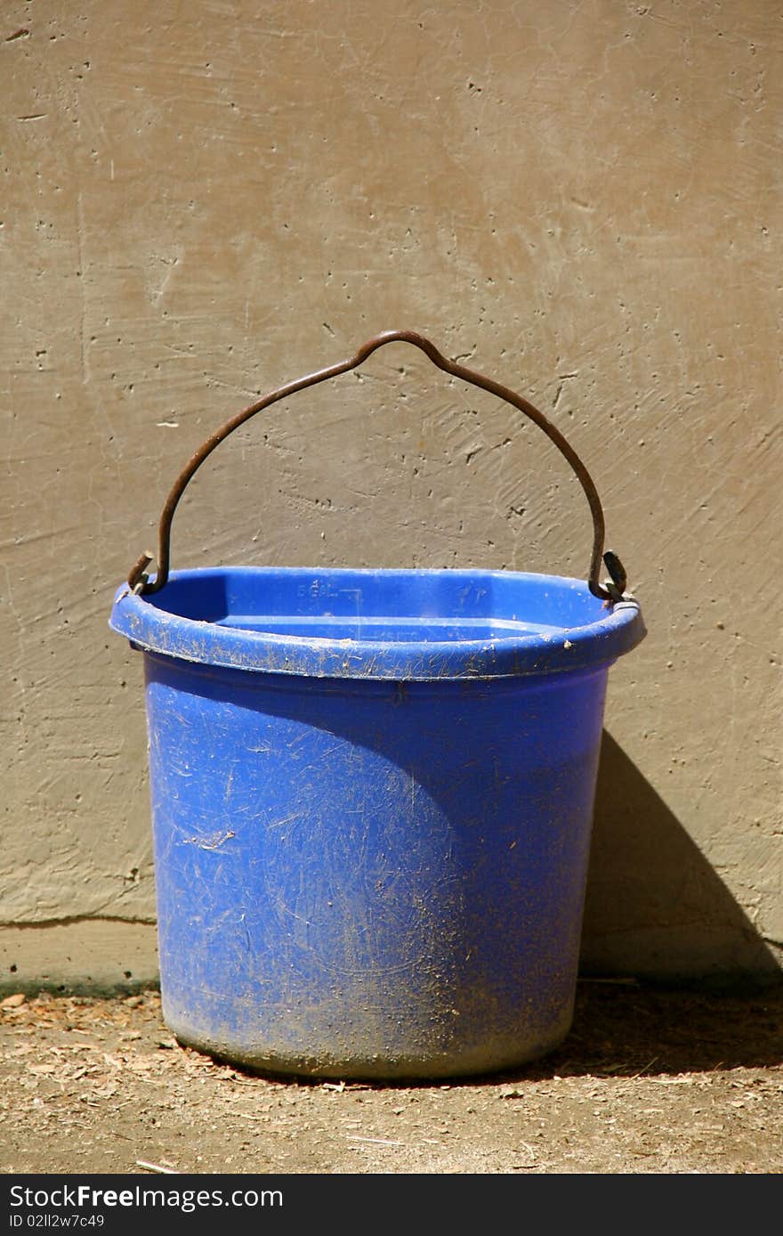 Blue bucket against a sandstone wall