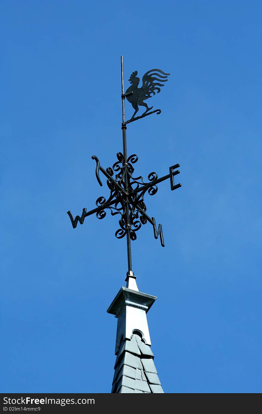 Rooster weather vane against blue sky