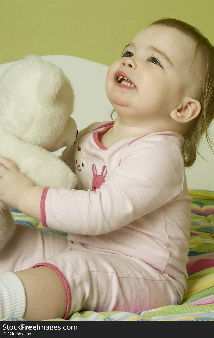 Baby girl laying on playing with a teddy bear. Baby girl laying on playing with a teddy bear