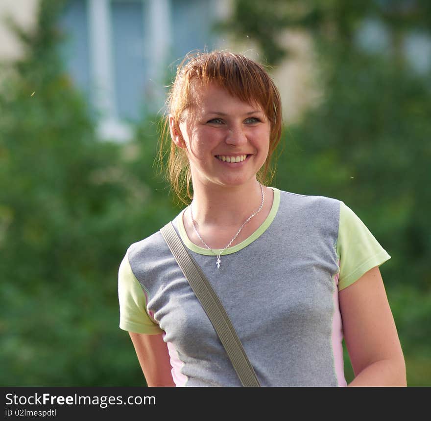 The young woman poses smiling on a background of green vegetation