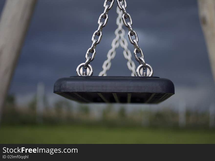 Low key image of a children's swing at a playground on a gloomy fall afternoon.