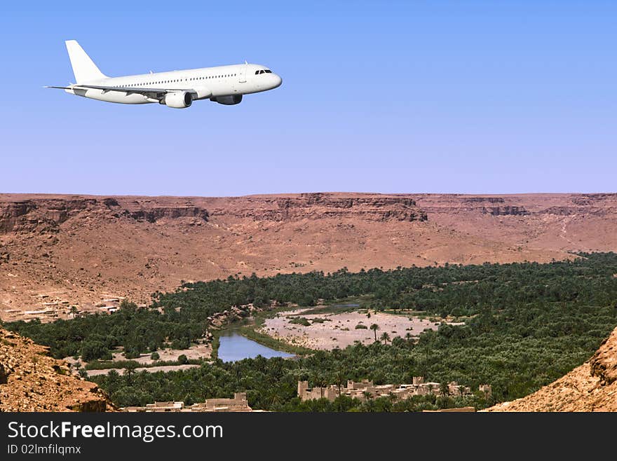 An airbus plane is flying over a saharan oasis. An airbus plane is flying over a saharan oasis.