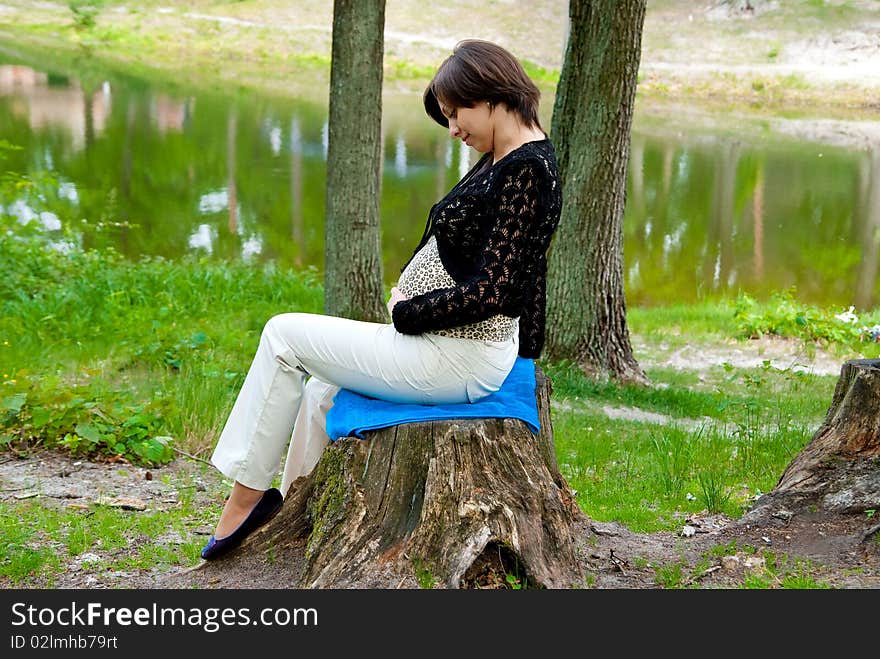 Beautiful pregnant girl in the park near lake.