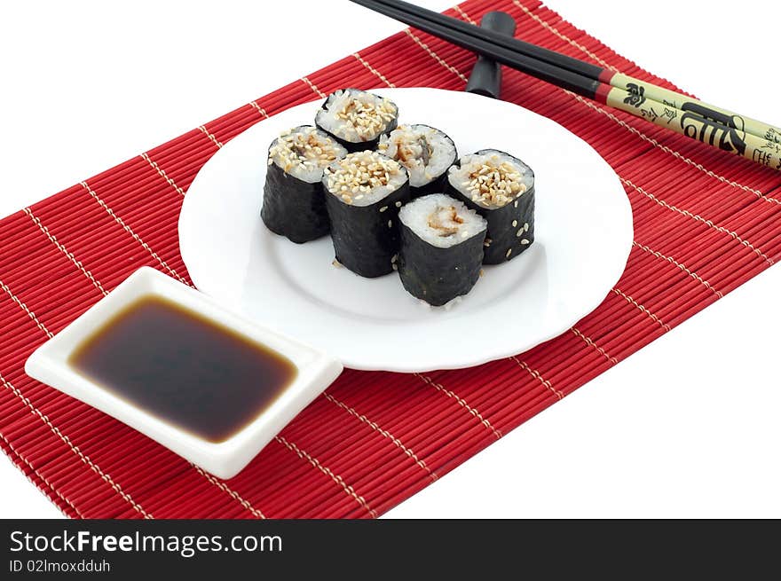 The Sushi, the chopsticks, soya sauce on a red bamboo mat on a white background. The Sushi, the chopsticks, soya sauce on a red bamboo mat on a white background