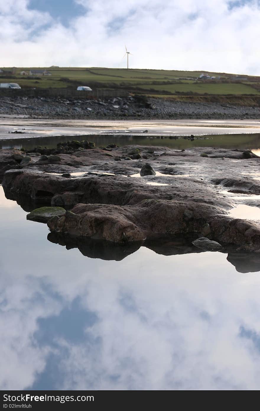 Rock pool on beale beach co kerry ireland on a cold winters morning with turbine in the background. Rock pool on beale beach co kerry ireland on a cold winters morning with turbine in the background