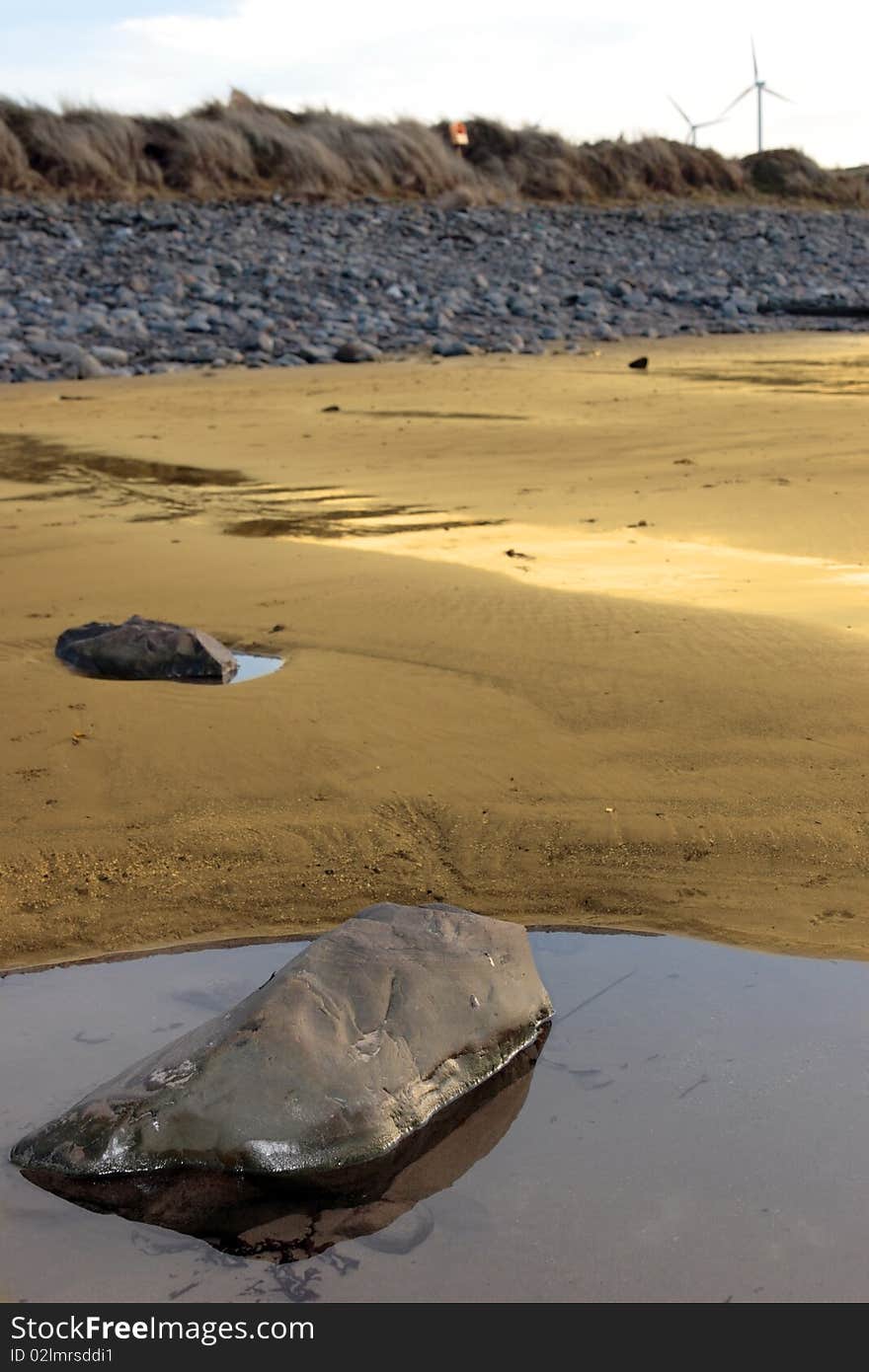 Rock pool on beale beach co kerry ireland on a cold winters morning with turbines in the background. Rock pool on beale beach co kerry ireland on a cold winters morning with turbines in the background