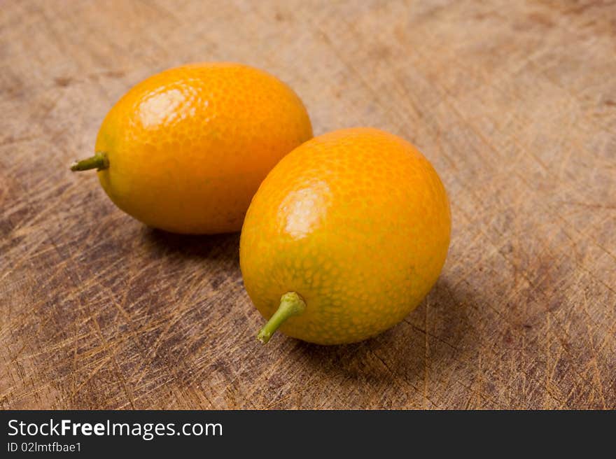 Two kumquats on old table.