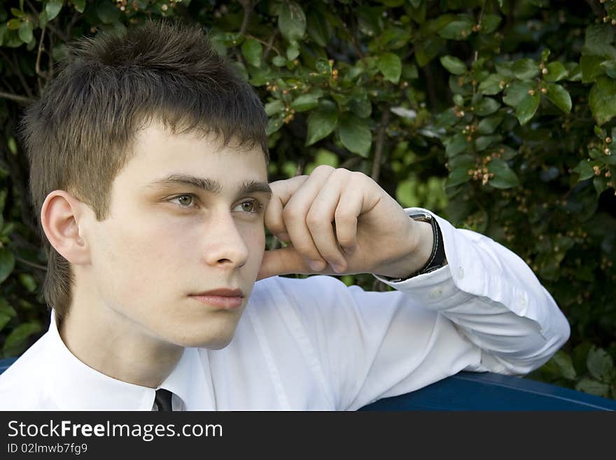 Guy in the park sits on a bench, propping up head on his hand, thinking. Guy in the park sits on a bench, propping up head on his hand, thinking