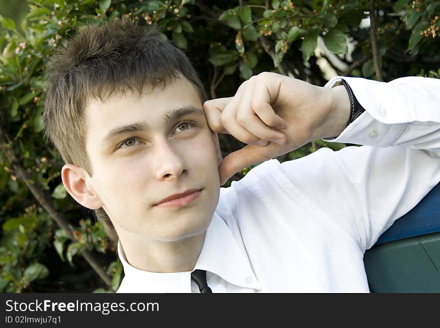 Guy in the park sits on a bench, propping up head on his hand, thinking. Guy in the park sits on a bench, propping up head on his hand, thinking