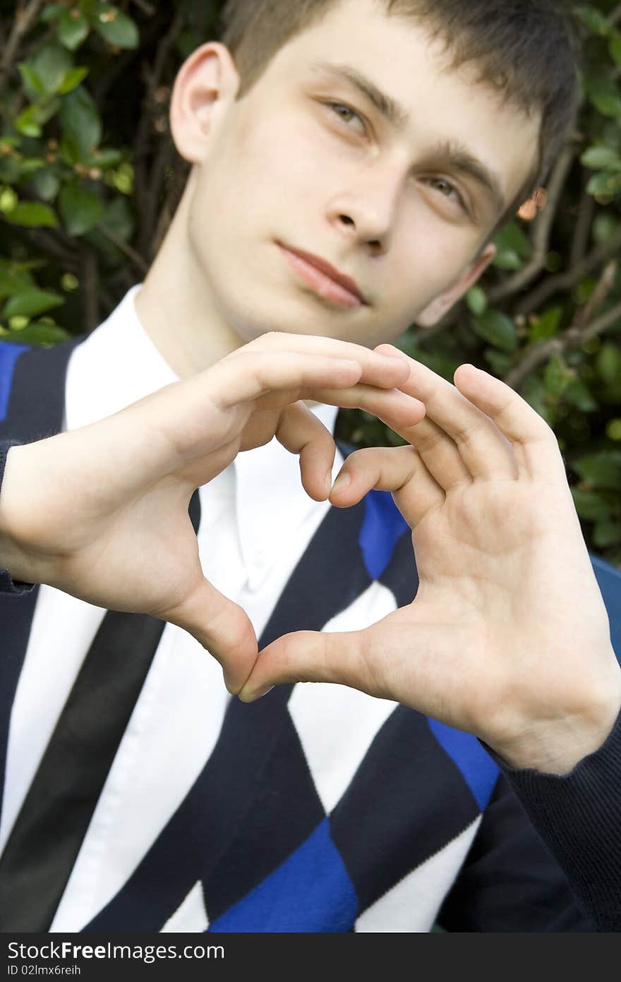 Teen boy in the park making heart shape with hands declaration of love