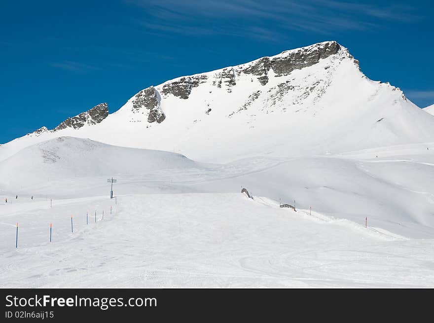 A view of alpine ski slope with a hight peak. A view of alpine ski slope with a hight peak.