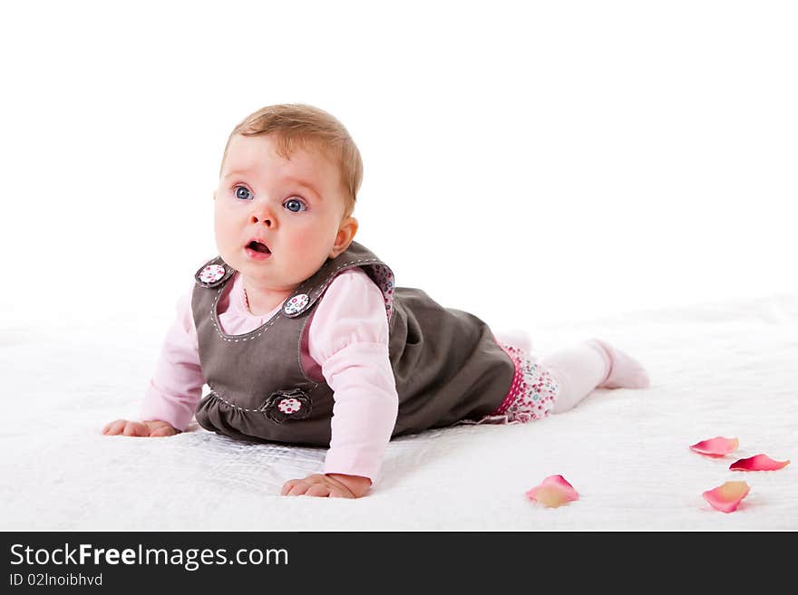 A baby girl is crawling along a floor with flower petals. Horizontal shot. A baby girl is crawling along a floor with flower petals. Horizontal shot.