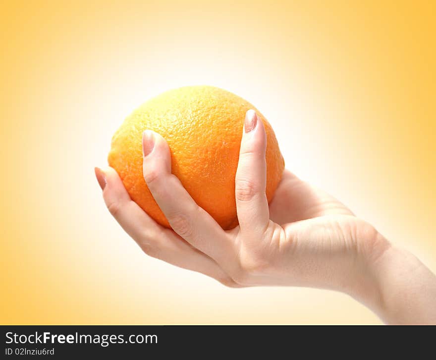 Image of a fresh and tasty orange in a human hand. Isolated on a ligh orange gradient background. Image of a fresh and tasty orange in a human hand. Isolated on a ligh orange gradient background.