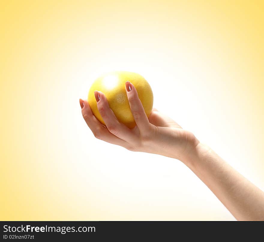 Image of a fresh and tasty lemon held in a human hand. Isolated on a ligh yellow gradient background. Image of a fresh and tasty lemon held in a human hand. Isolated on a ligh yellow gradient background.