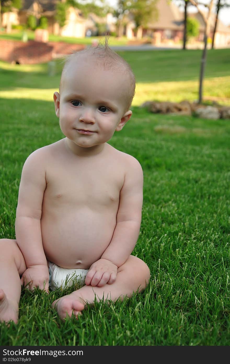 Smiling baby boy sitting in grass. Smiling baby boy sitting in grass