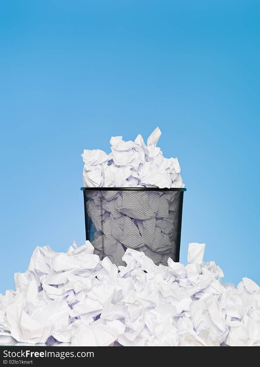 Filled wastebasket on blue background