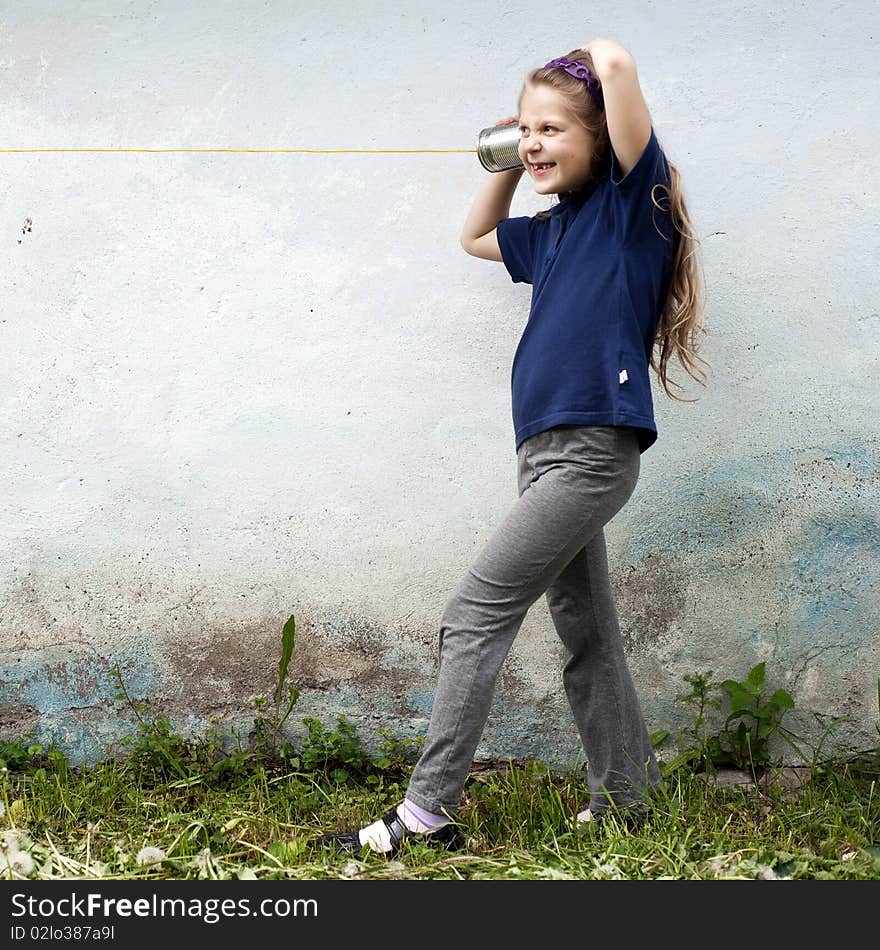 An image of a girl  with a toy-telephone outdoors. An image of a girl  with a toy-telephone outdoors