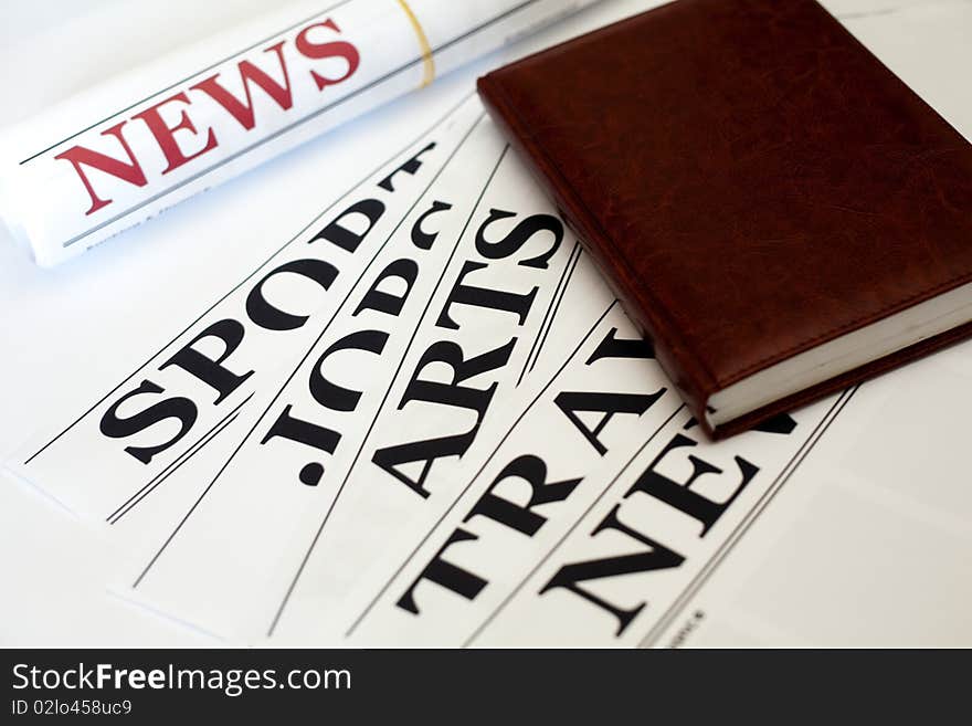 An image of a notebook and a newspaper. An image of a notebook and a newspaper