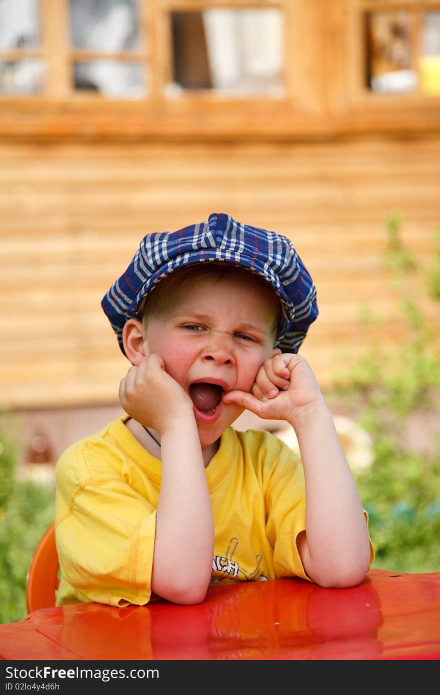 Boy yawing while waiting for his dinner outdoor. Boy yawing while waiting for his dinner outdoor