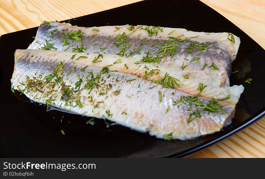 Herring on black plate on wood board