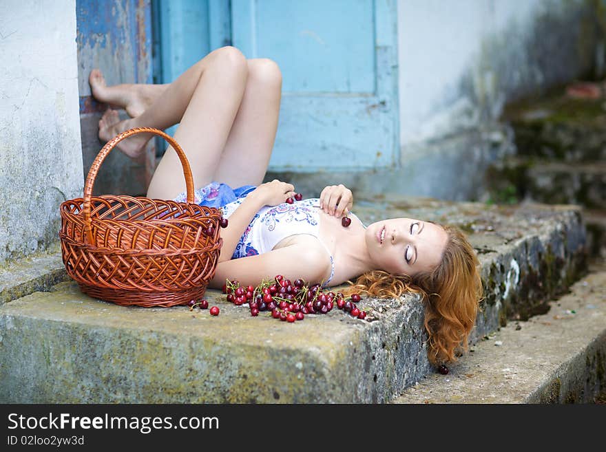 Red-haired beauty in a summer sarafan eating cherries